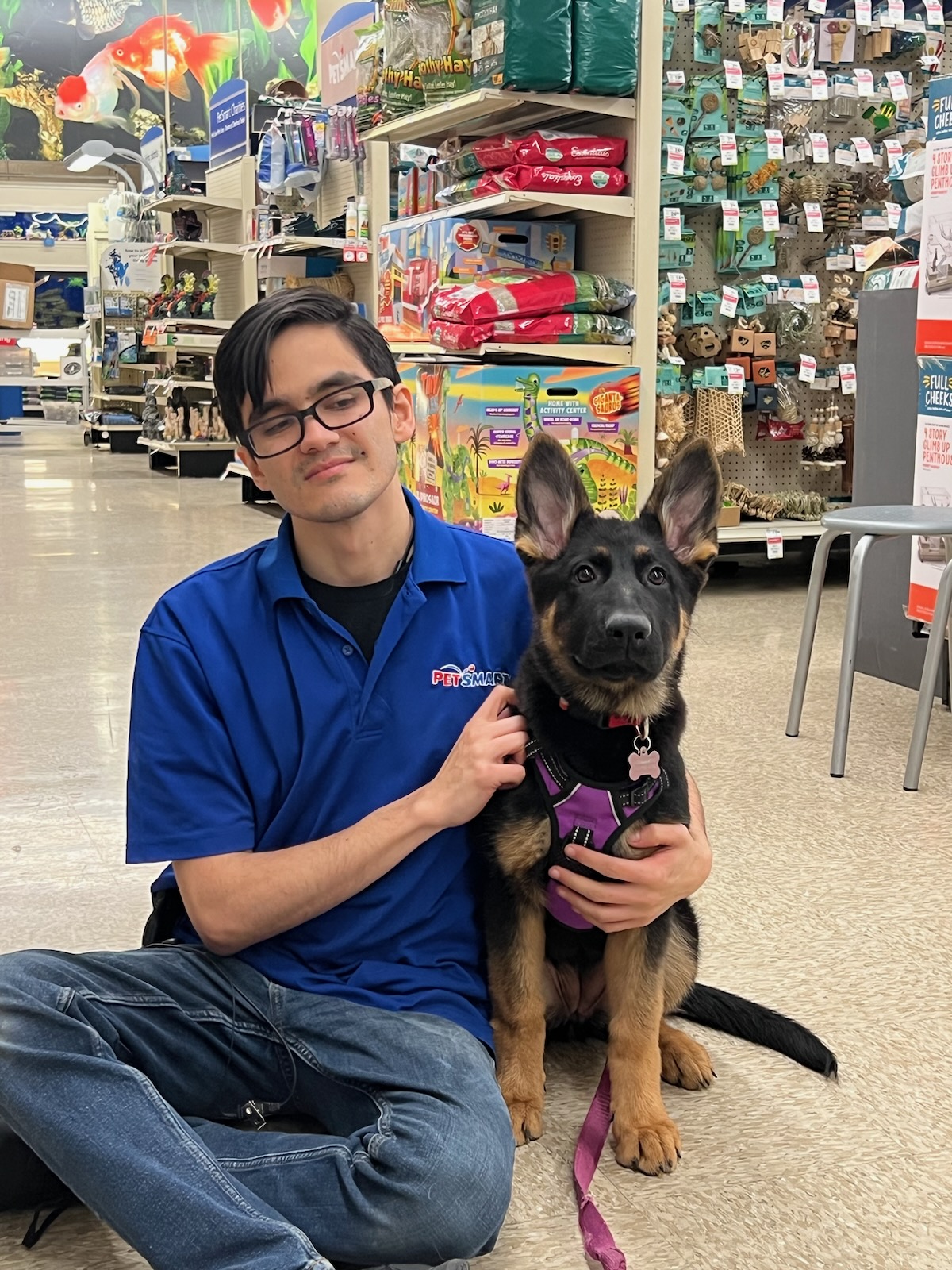 Myself, Gunner Yoder, sitting on the floor of a PetSmart hugging a GSD puppy